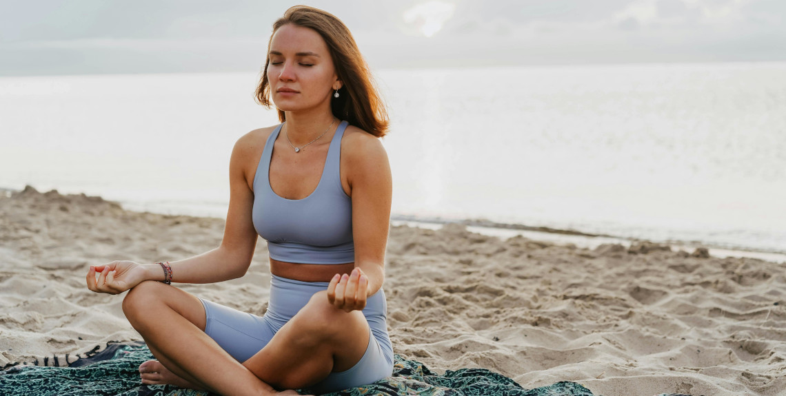 Frau bei transzendentaler Meditation am Strand