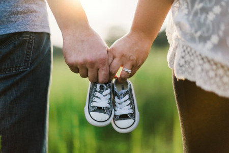 Zwei Hände halten ein paar Kinderschuhe