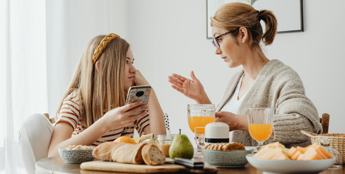 Mutter am vollen Frühstückstisch im Gespräch mit ihrer Tochter Mutter am vollen Frühstückstisch im Gespräch mit ihrer Tochter