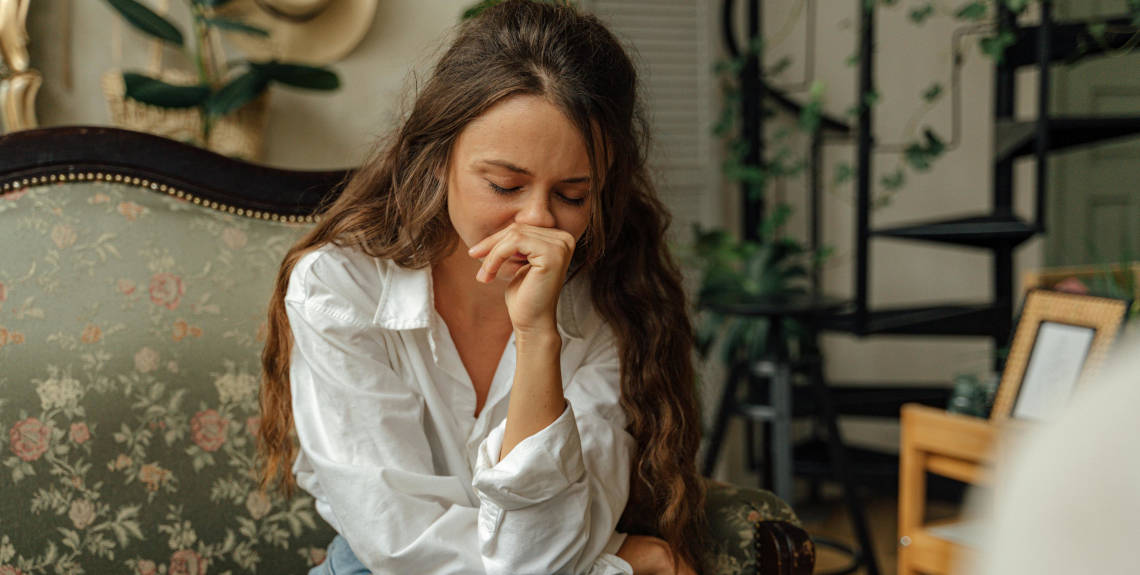 Frau sitzt traurig auf einem Sessel Frau sitzt traurig auf einem Sessel